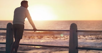 a man looking at the ocean from a pier