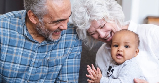 African American grandparents with grandmother holding baby grandchild on her lap