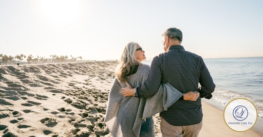 Middle-aged couple strolling on the beach with their arms wrapped around each other.
