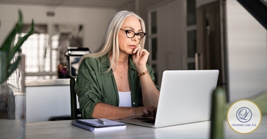 Woman sitting at a table looking at her laptop.