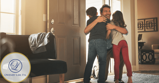 Image of father happily hugging his young son and daughter