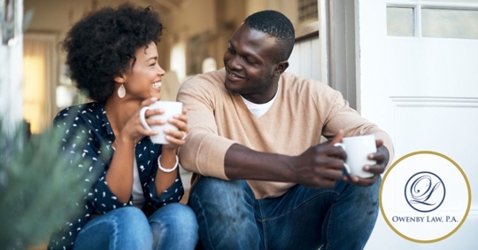 African American couple sitting on doorstep drinking coffee